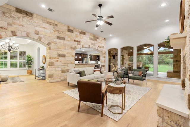 living room with ceiling fan with notable chandelier and light hardwood / wood-style flooring