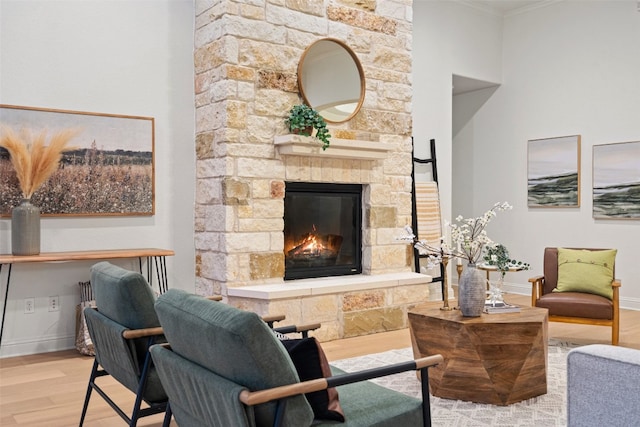 living room featuring a fireplace, ornamental molding, and light hardwood / wood-style flooring