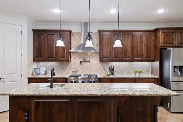 kitchen featuring sink, wall chimney exhaust hood, stainless steel fridge, decorative light fixtures, and dark brown cabinetry