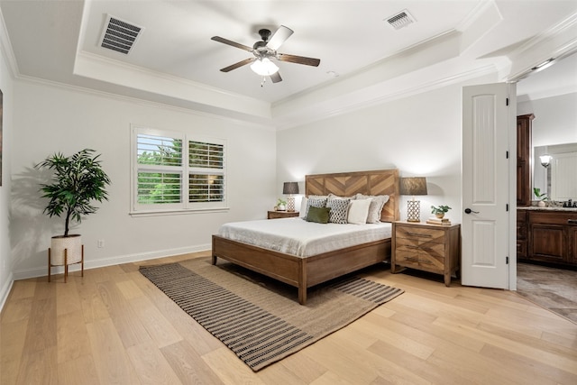 bedroom with ceiling fan, a raised ceiling, ornamental molding, and connected bathroom