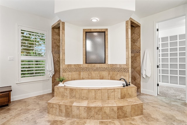 bathroom featuring tiled bath and a wealth of natural light