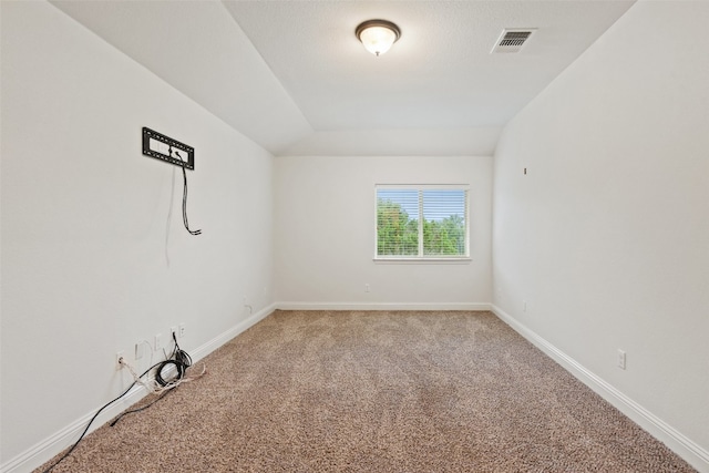 carpeted empty room featuring vaulted ceiling