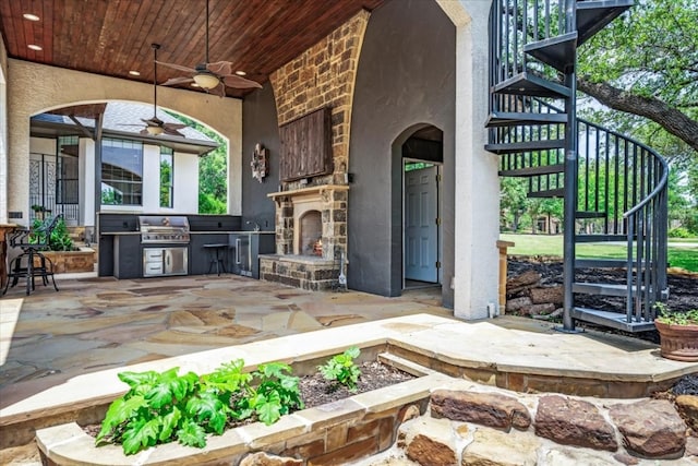 view of patio / terrace with ceiling fan, area for grilling, exterior kitchen, and an outdoor stone fireplace