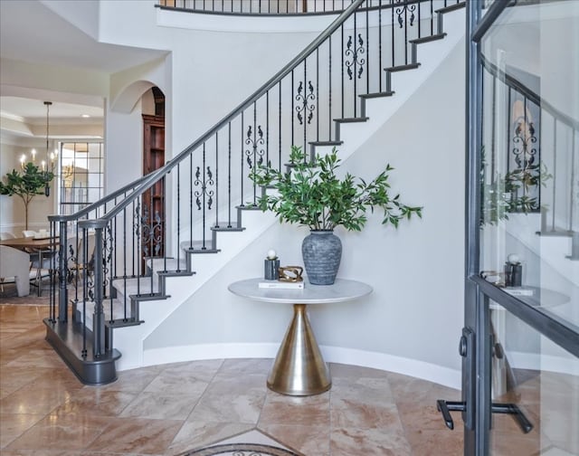 stairs with a towering ceiling, ornamental molding, and tile floors