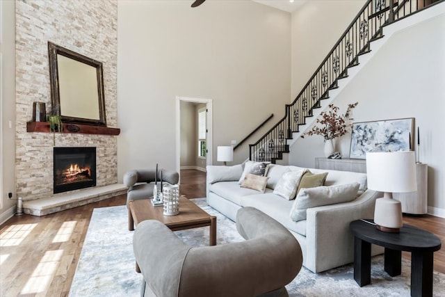 living room featuring wood-type flooring, a towering ceiling, and a fireplace