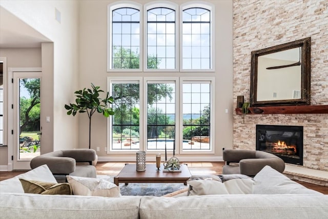 living room featuring a high ceiling, a fireplace, and wood-type flooring