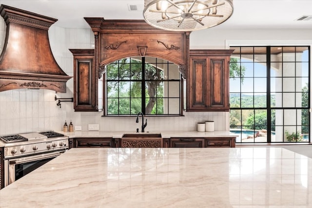 kitchen with plenty of natural light, premium range hood, sink, and high end stove