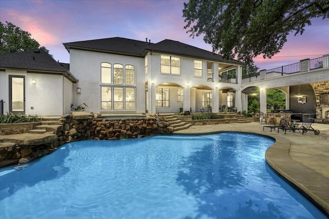 pool at dusk featuring a patio area