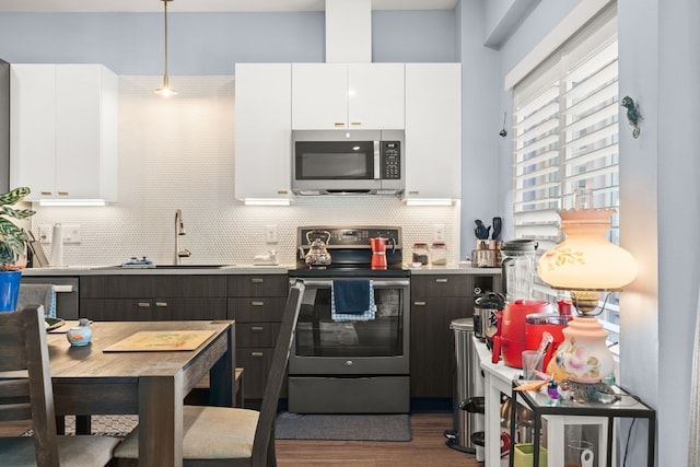 kitchen featuring stainless steel appliances, pendant lighting, backsplash, sink, and white cabinetry