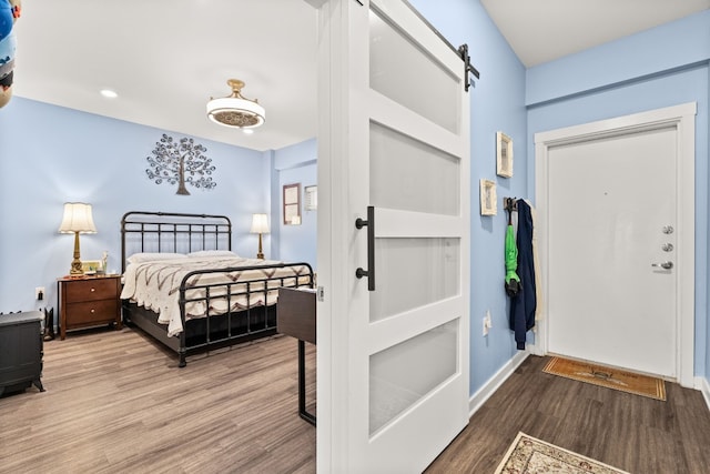 bedroom featuring wood-type flooring and a barn door