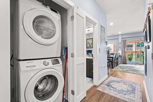 clothes washing area with stacked washer / dryer and wood-type flooring