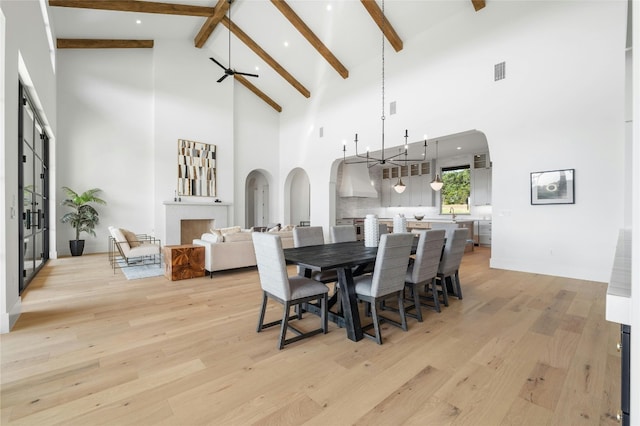 dining room featuring a chandelier, light wood-type flooring, visible vents, and beamed ceiling