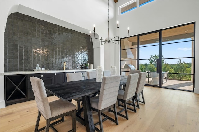 dining room with light wood-style floors, a high ceiling, and a chandelier