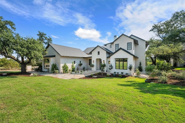 view of front of property with a front yard, metal roof, and stucco siding