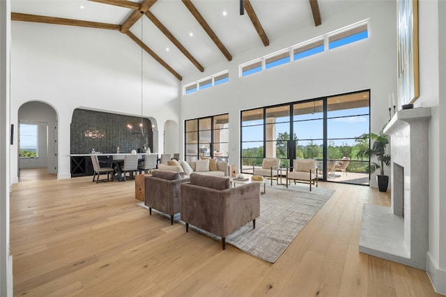 living room with light wood-type flooring, a high ceiling, and a premium fireplace