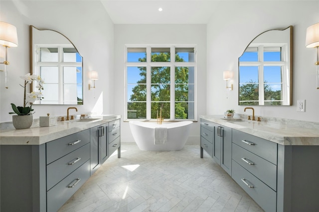 full bathroom featuring two vanities, a sink, and a wealth of natural light