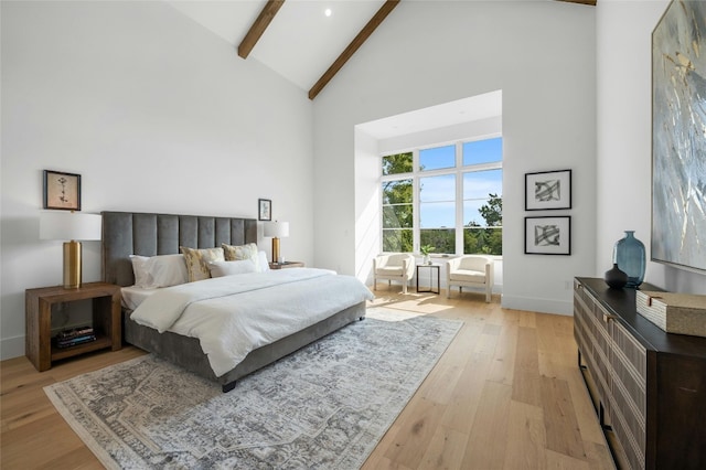 bedroom with high vaulted ceiling, beamed ceiling, and light wood-style floors