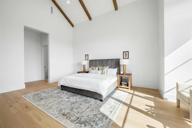 bedroom featuring high vaulted ceiling, beamed ceiling, wood finished floors, and baseboards