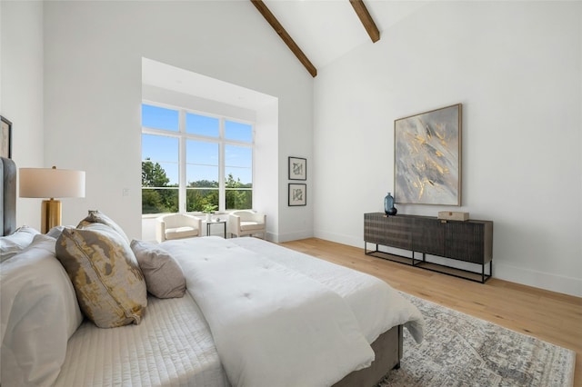 bedroom featuring baseboards, high vaulted ceiling, beamed ceiling, and wood finished floors