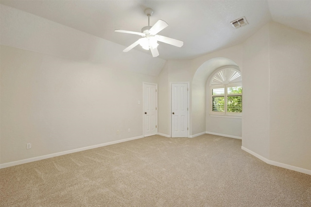 spare room featuring ceiling fan, light carpet, and vaulted ceiling