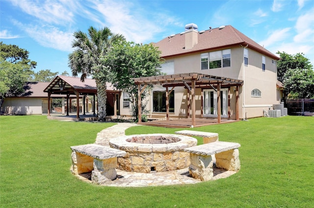 back of house with a fire pit, central AC unit, a pergola, and a yard