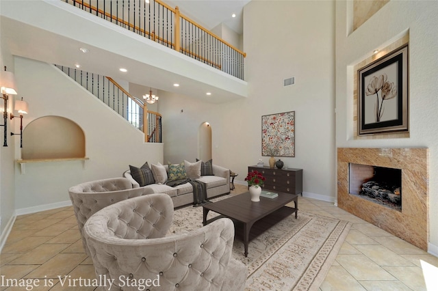 living room with a high end fireplace, light tile patterned flooring, and a high ceiling