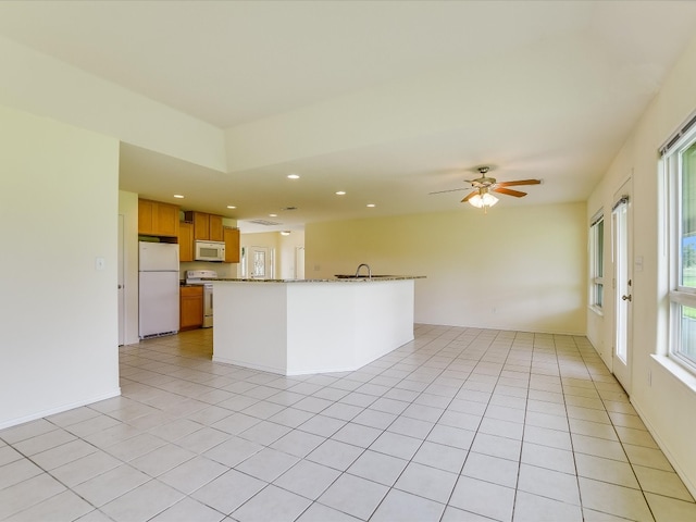 kitchen featuring light stone countertops, white appliances, sink, light tile flooring, and ceiling fan