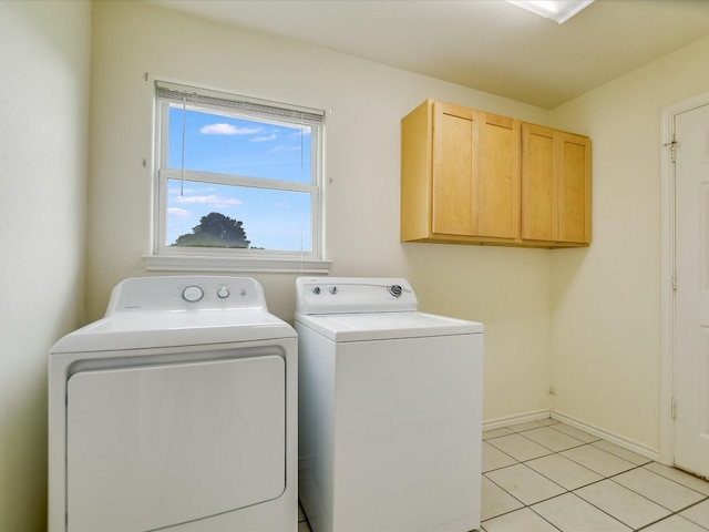 clothes washing area with independent washer and dryer, light tile flooring, and cabinets