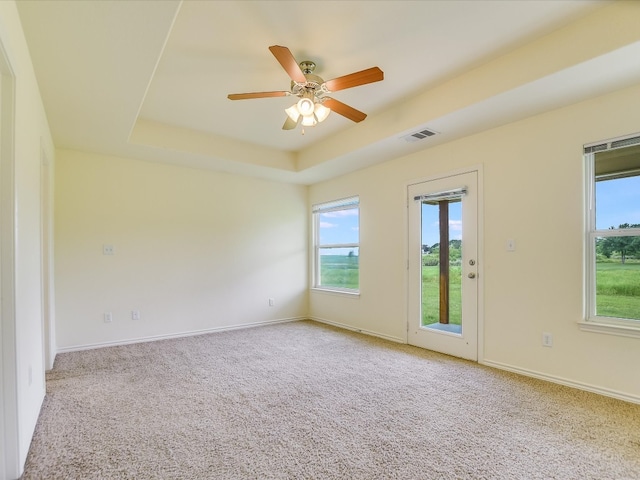 spare room with carpet, a raised ceiling, and ceiling fan