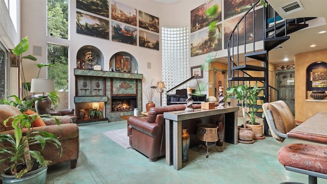 living room with a premium fireplace, a high ceiling, and concrete flooring