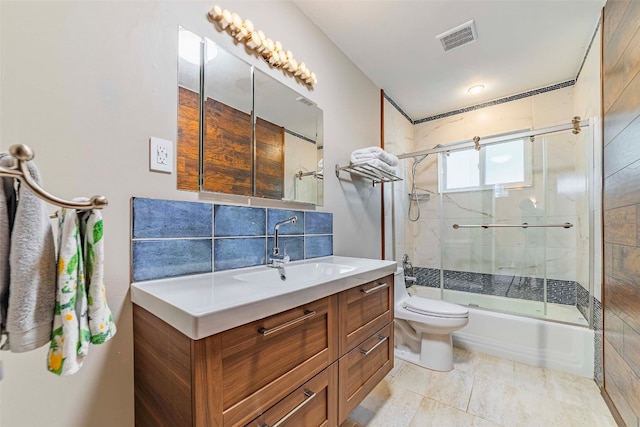 full bathroom featuring shower / bath combination with glass door, tile flooring, tile walls, vanity, and toilet