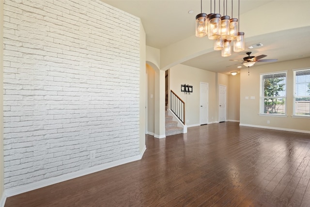 interior space with dark wood-type flooring, brick wall, and ceiling fan