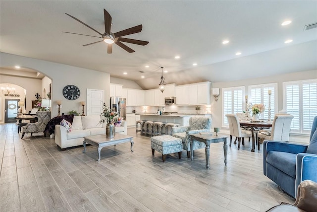 living room with ceiling fan, sink, light hardwood / wood-style floors, and vaulted ceiling