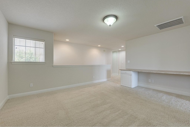 interior space with a textured ceiling and light colored carpet