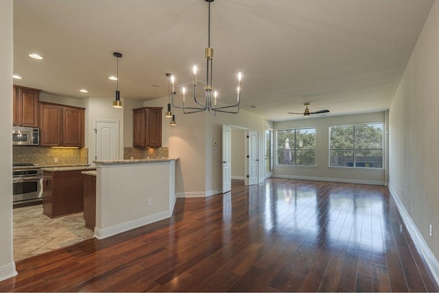 kitchen with dark hardwood / wood-style floors, ceiling fan with notable chandelier, decorative backsplash, stainless steel appliances, and decorative light fixtures