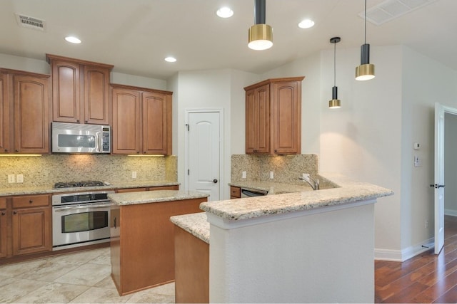 kitchen featuring appliances with stainless steel finishes, backsplash, a kitchen island, and pendant lighting