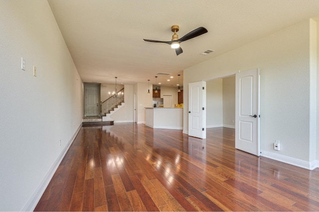 unfurnished living room with ceiling fan with notable chandelier and dark hardwood / wood-style floors