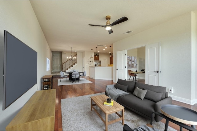 living room with ceiling fan with notable chandelier and hardwood / wood-style floors