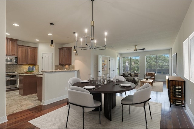 dining room with ceiling fan with notable chandelier and hardwood / wood-style flooring