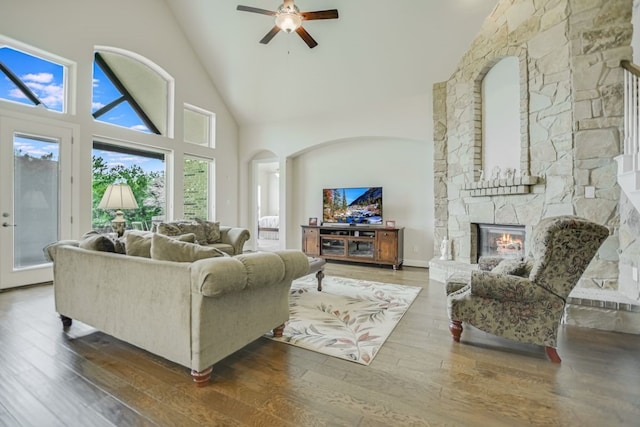 living room featuring high vaulted ceiling, hardwood / wood-style floors, ceiling fan, and a fireplace