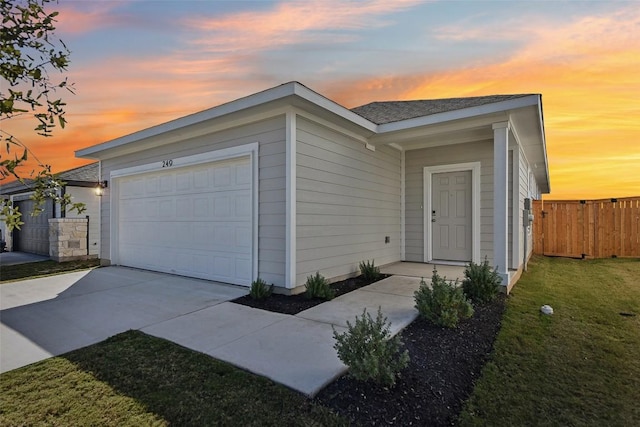 view of front of house featuring a front lawn, fence, driveway, and an attached garage