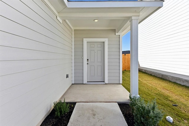 property entrance with a lawn and fence