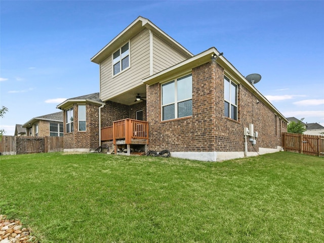 back of property with a yard, a deck, and ceiling fan