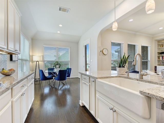 kitchen featuring lofted ceiling, white cabinets, hanging light fixtures, dark hardwood / wood-style flooring, and light stone counters