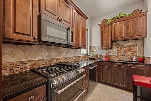 kitchen with tasteful backsplash, sink, appliances with stainless steel finishes, light tile patterned floors, and dark stone counters