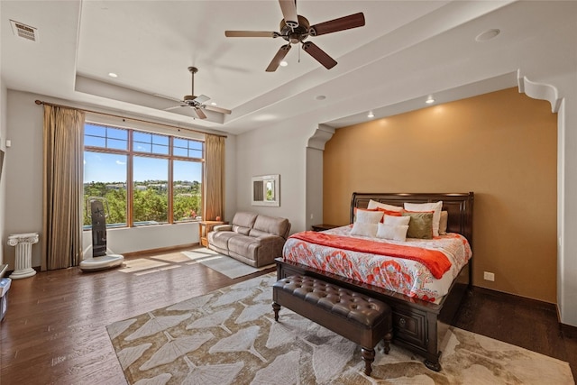 bedroom featuring a raised ceiling, ceiling fan, and dark hardwood / wood-style floors