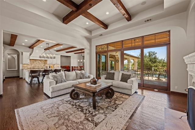 living room with a high ceiling, dark wood-type flooring, beamed ceiling, and an inviting chandelier