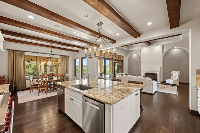 kitchen featuring white cabinetry, stainless steel appliances, a notable chandelier, a kitchen island with sink, and sink