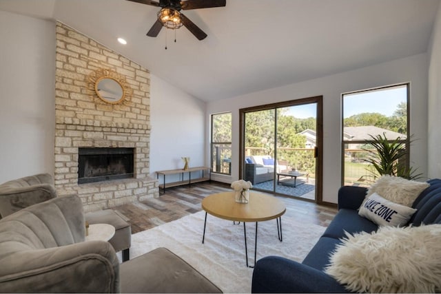 living room with ceiling fan, a fireplace, vaulted ceiling, and light wood-type flooring