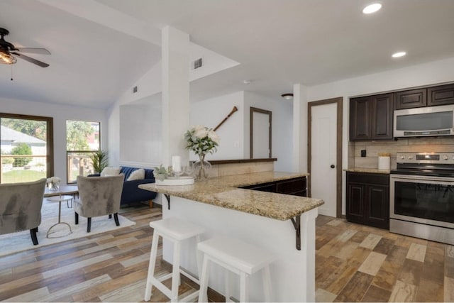 kitchen with a kitchen breakfast bar, kitchen peninsula, tasteful backsplash, and stainless steel appliances